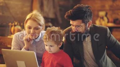 可爱的小男孩看着笔记本电脑屏幕，和父母在家看动画片。 快乐的<strong>爸爸妈妈</strong>和小男孩